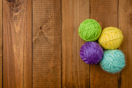 Yarn in a basket. Colorful balls of wool on wooden table. Variety of yarn balls, view from above.
