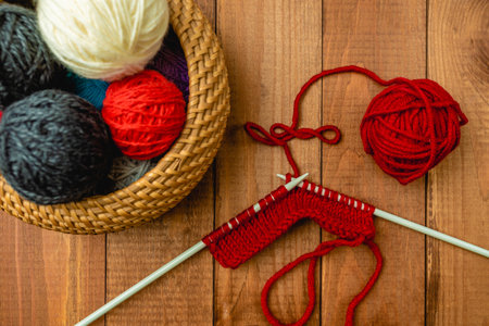 Basket with multi-colored yarn on a wooden table and knitting needles.の写真素材