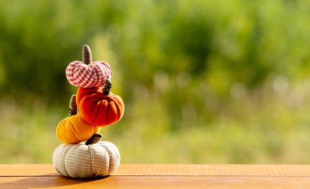 Pumpkins sewn from fabric on a wooden table against a background of greenery. Cool pumpkins. Halloween concept.の写真素材