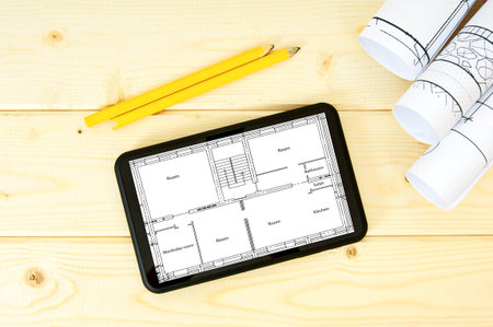 Planning of construction of the house. Tablet, drawings and pencils on a wooden background.