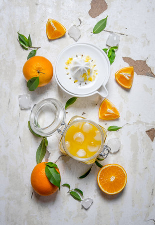 Fresh orange juice with ice, with slices of oranges and a juicer. On rustic background. Top viewの写真素材