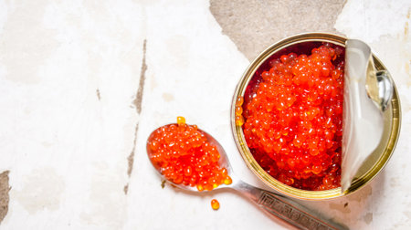 Red caviar in tin can and spoon. On rustic background. Free space for text . Top viewの写真素材