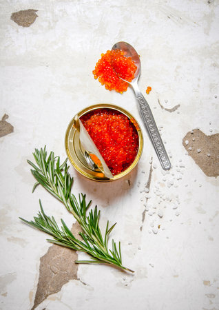 The concept of red caviar. Red caviar with rosemary. On rustic background. Top viewの写真素材
