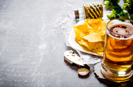 Beer background . Beer and chips on a old stone background.の写真素材