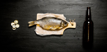 The beer concept . Dried fish and beer bottle on the black board. Top view