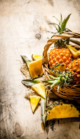 Fresh pineapples in the basket. On a wooden table.の写真素材