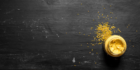 Fresh mustard in jar with seeds. On a black chalkboard.