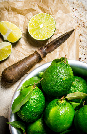 Sliced limes with a knife and a bowl . On the rustic background.の写真素材