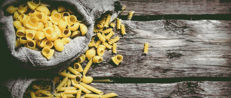 Several types of pasta in old bags. On wooden background. Free space for text . Top viewの写真素材