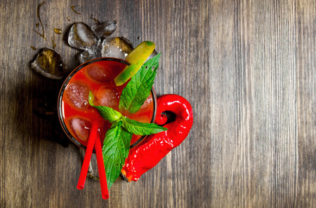 The cocktail bloody mary . Cocktail with ice and ingredients on wooden background . Free space for...