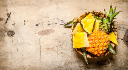 Fresh pineapple , chopped and whole in your shopping cart . On a wooden table. Free space for text . Top viewの写真素材