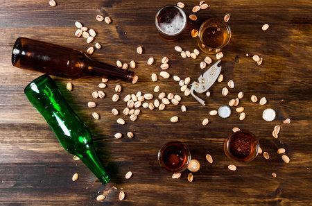 Beer background. Four beers with pistachios on a wooden table. Top viewの写真素材