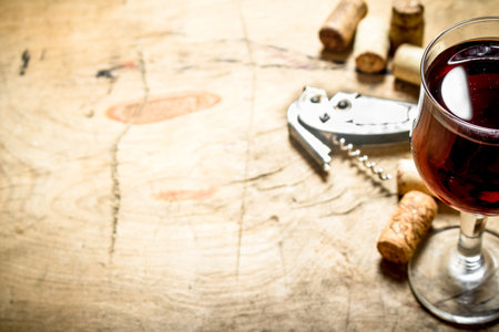 glass of red wine with corks and a corkscrew. On wooden background.の写真素材
