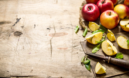 Red apples sliced with a knife. On wooden background. Free space for text .の写真素材