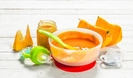 Baby food. Puree from fresh pumpkin. On a white wooden background.の写真素材