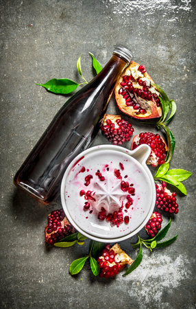 The pomegranate juice in a bottle with the juice and slices of ripe pomegranate. On the stone table. Top viewの写真素材