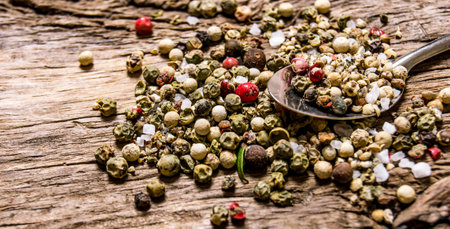 Spicy peppercorns in a spoon. On a wooden background.の写真素材