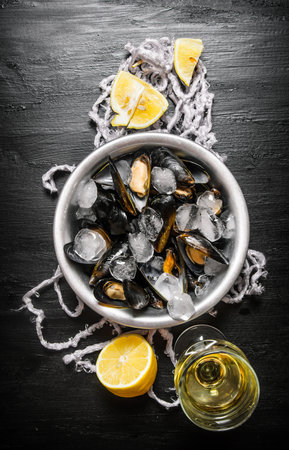 Clams in a cup with ice, wine and lemon. On a black wooden background. Top viewの写真素材