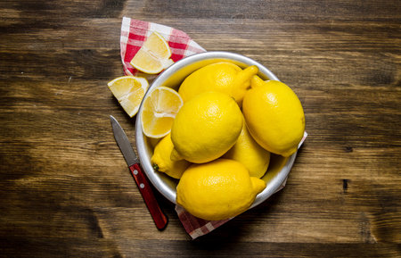 The lemons in the cup with a knife on the fabric. On a wooden table. Top viewの写真素材
