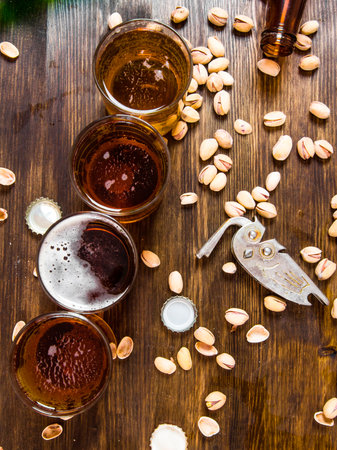 Beer background. Four beers with pistachios on a wooden table. Top view