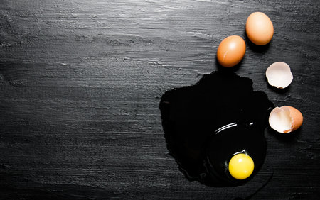 Broken egg . On a black wooden background. Free space for text . Top viewの写真素材