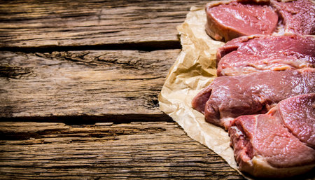 Raw fresh meat on paper. On the wooden background. Free space for text .の写真素材