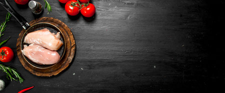 Raw chicken fillet with tomatoes and herbs. On the black chalkboard.の写真素材