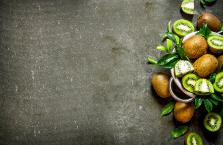 Fresh kiwi fruit in a pan with the leaves. On the stone table. Free space for text . Top viewの写真素材