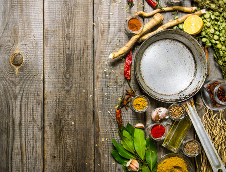Empty frying pan with aromatic spices and herbs. On a wooden table. Free space for text . Top viewの写真素材