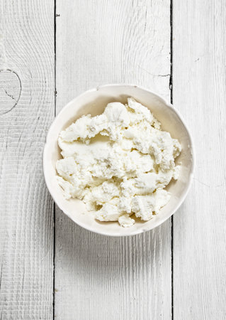 Cheese from fresh milk. On a white wooden background.