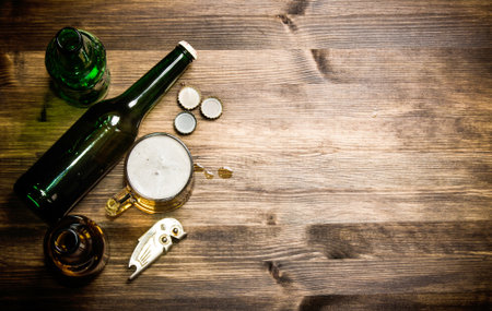 Beer style - bottle, beer in the glass and covers on wooden table. Free space for text. Top viewの写真素材