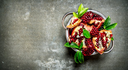 Ripe pomegranate with leaves in a saucepan. On the stone table. Free space for text . Top viewの写真素材