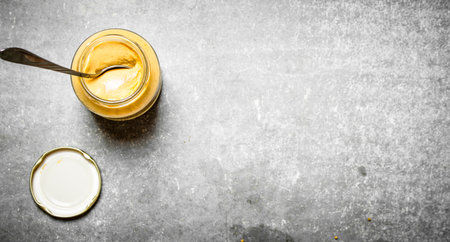 Fresh mustard in a jar with a spoon. On the stone table.の写真素材