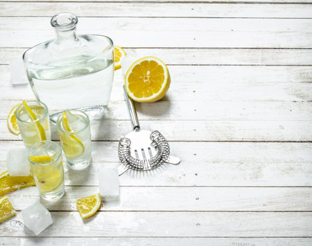 Vodka shots with lemon and ice. On a white wooden table.の写真素材