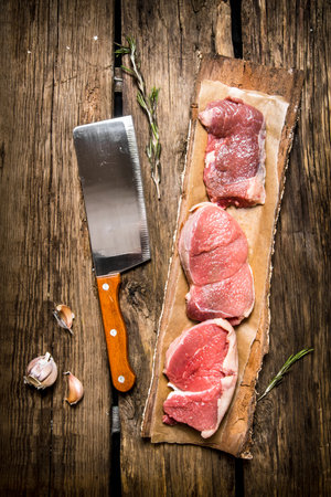 Fresh steak from raw meat and spices and chopping knife. On wooden background Top viewの写真素材