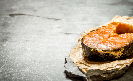 piece of fried salmon on the paper. On the stone table.の写真素材