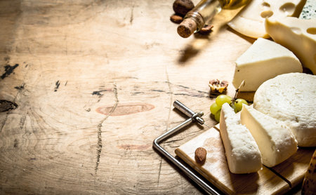 White wine with different types of cheese. On a wooden table.の写真素材