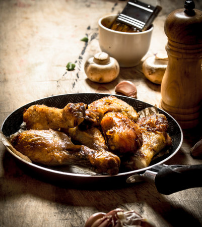 Fried chicken legs in a pan with tomato sauce, mushrooms and garlic.の写真素材