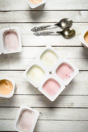 Fruit yogurt with spoons. On a white wooden table.の写真素材