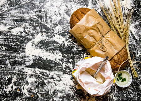 Fresh ciabatta with a bag of flour and ears of wheat. On the Board with flour. Free space for text . Top viewの写真素材