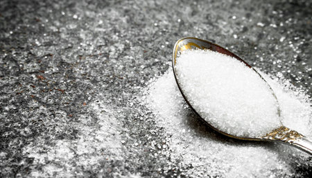 Sugar in a teaspoon. On a rustic background.