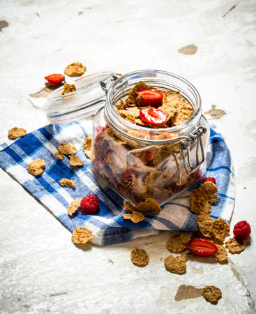 Fitness food. Muesli with berries in a jar on the fabric. On rustic background.
