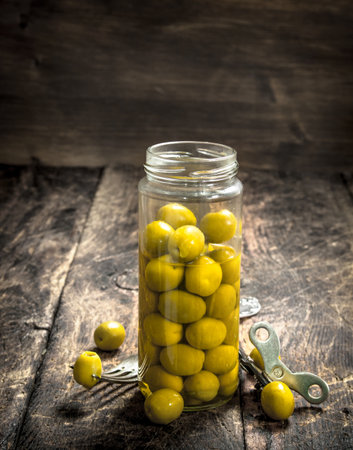 Pickled olives in glass jar. On a wooden backgroundの写真素材