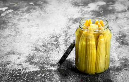 Marinated corn in glass jar. On a rustic background.の写真素材