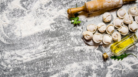 Homemade ravioli with olive oil and with a rolling pin. On the stone table with flour. Free space for text . Top viewの写真素材