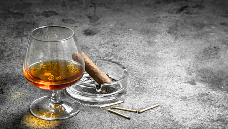 glass of cognac with a cigar. On a rustic background.の写真素材