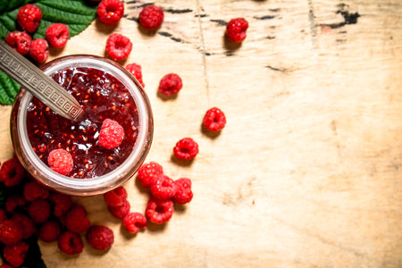Sweet jam with raspberries. On a wooden table.