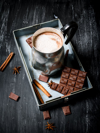 Hot chocolate with cinnamon and bitter chocolate. On black rustic background.の写真素材