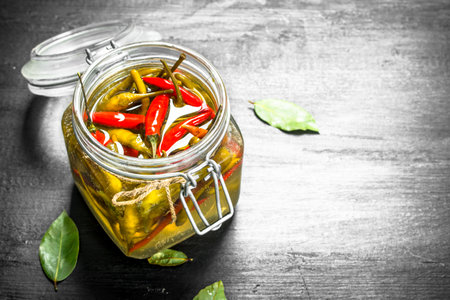 Pickled hot chili peppers in glass jar. On the black chalkboard.の写真素材