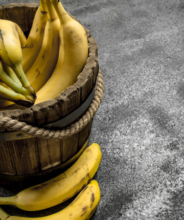 Ripe bananas in a wooden bucket. On a rustic background.の写真素材